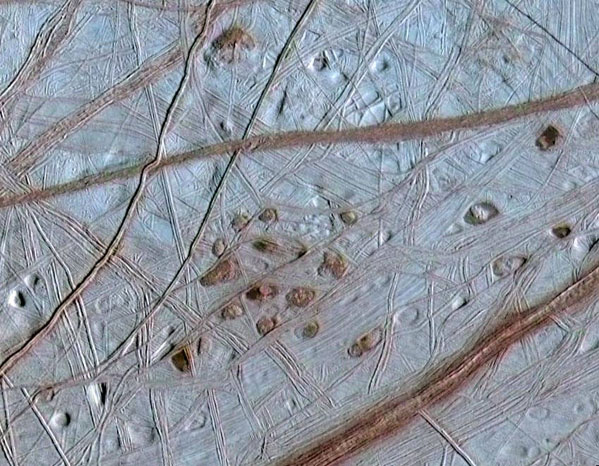 Reddish spots and hallow pits pepper the ridged surface of Jupiter's moon, Europa, in this view combining information from the images taken by NASA's Galileo spacecraft during two different orbits around Jupiter. (Credit: NASA)