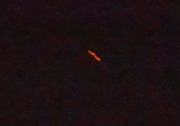 The witness first saw an unusual star-like object and several minutes later the cross-shaped object appeared much lower in altitude just above the tree line. This is a cropped and enlarged version of the witness photograph. (Credit: MUFON)