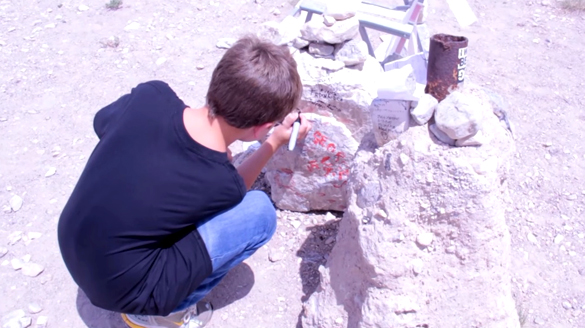 Hasvold's son signs a rock at what remains of the black mailbox. (Credit: Jeremiah Hasvold/YouTube)