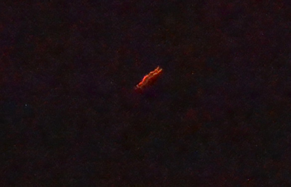 The witness reported that the object looked like a cross as it moved just above the tree line on June 4, 2014. The image was cropped and enlarged. (Credit: MUFON)