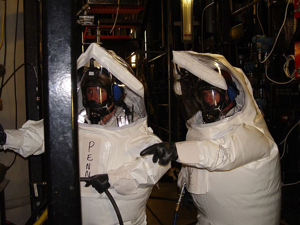 Two workers in demilitarization protective ensemble (DPE) performed maintenance work in an area of the Newport Chemical Agent Disposal Facility (NECDF) where chemical agent may have been present. (Credit: Wikimedia Commons)